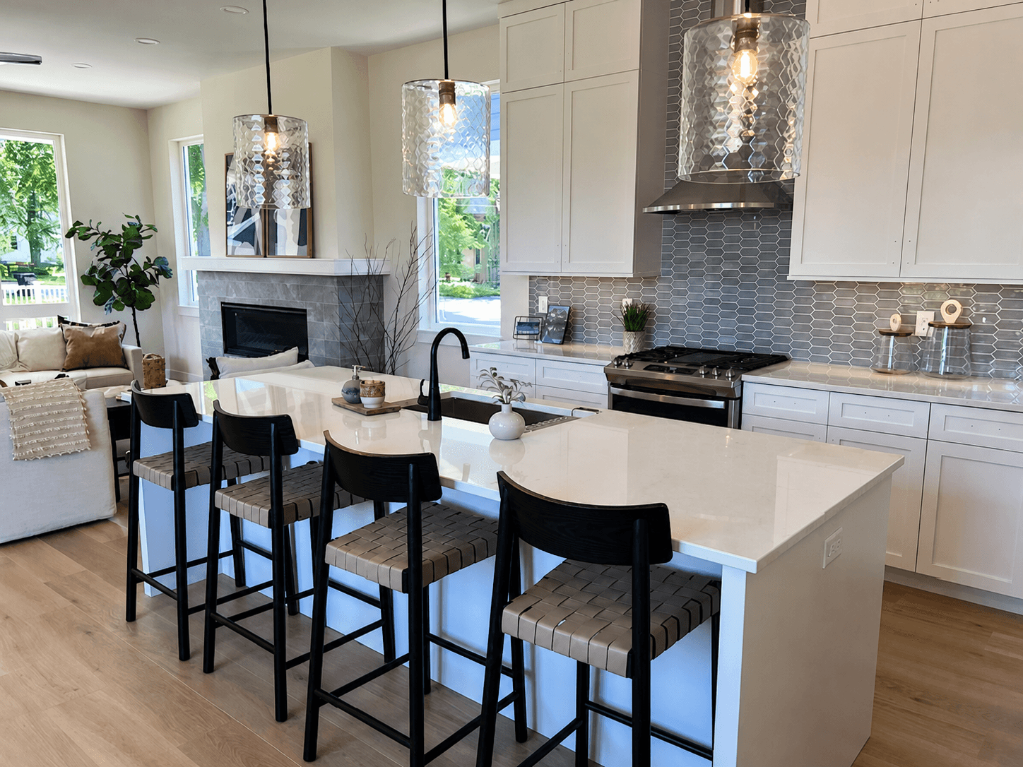 White custom kitchen with three glass pendant lights over the island, electrical finish by Greatland Electric
