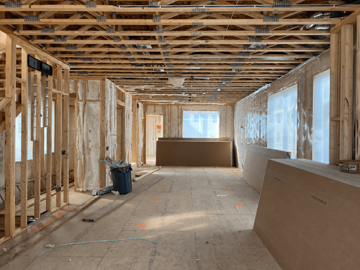 Framed custom home interior with insulation and trusses at the electrical rough-in planning stage