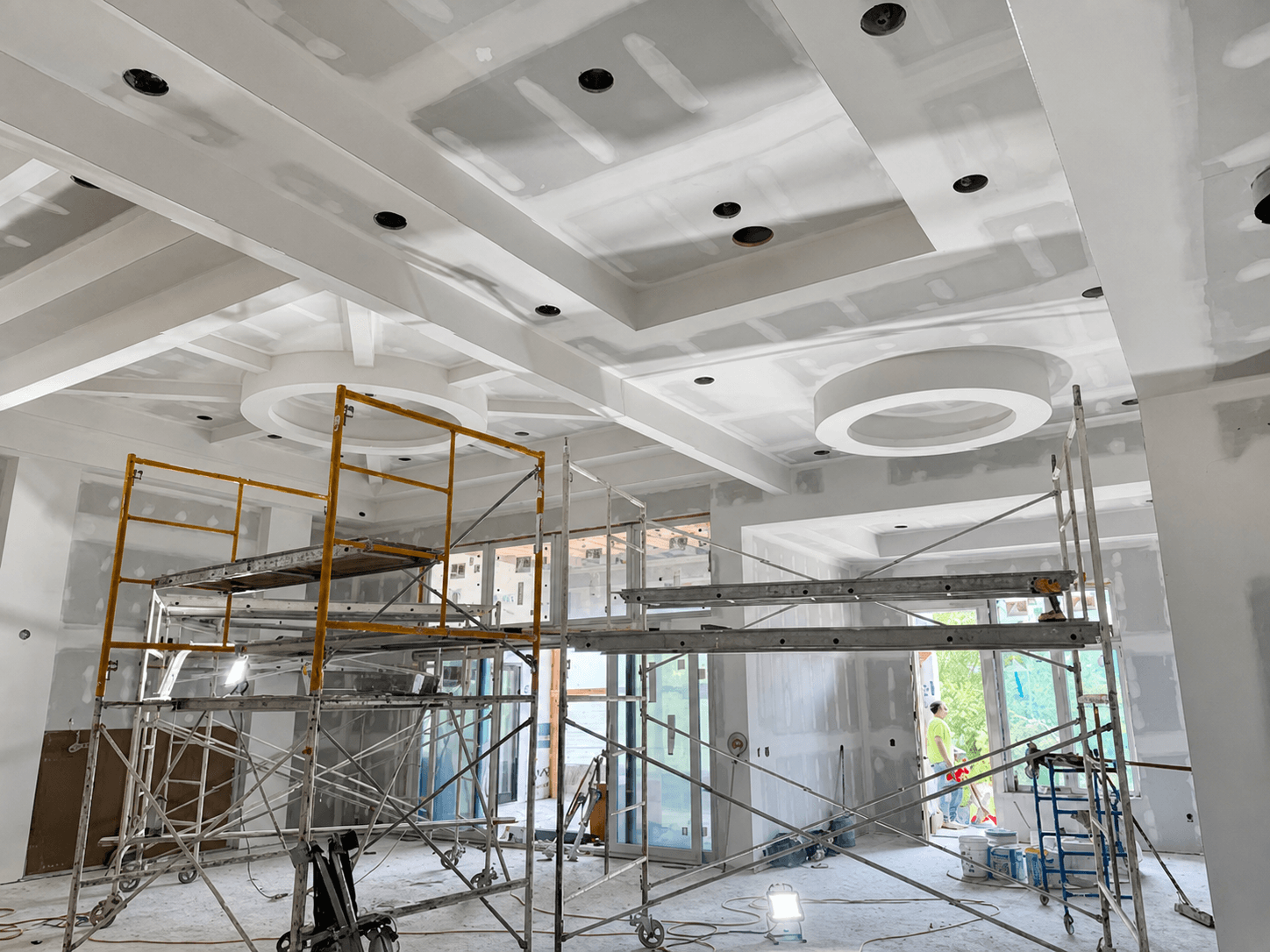 Scaffolding beneath a coffered ceiling with recessed light cans installed during custom home construction